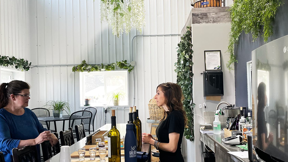 Inside clubhouse with a wine-tasting table, cute tables, hanging greenery